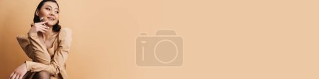Téléchargez les photos : Jeune femme asiatique souriant tout en posant avec friseur de cils isolé sur fond beige - en image libre de droit