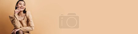 Téléchargez les photos : Jeune femme asiatique souriant tout en posant avec friseur de cils isolé sur fond beige - en image libre de droit