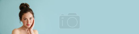 Téléchargez les photos : Femme brune à moitié nue posant et regardant la caméra isolée sur fond bleu - en image libre de droit