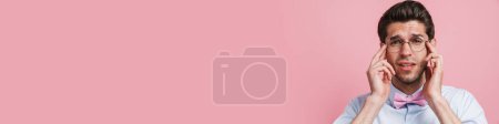 Photo for Young white man in eyeglasses with headache rubbing his temples isolated over pink background - Royalty Free Image