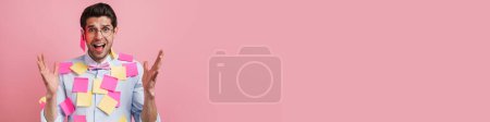 Photo for Young white man with stickers gesturing and screaming at camera isolated over pink background - Royalty Free Image