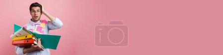 Téléchargez les photos : Jeune homme blanc choqué avec des autocollants posant avec des cas de documents isolés sur fond rose - en image libre de droit
