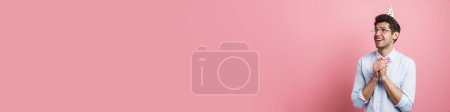 Téléchargez les photos : Jeune homme blanc portant nœud papillon et cône de fête souriant et gestuel isolé sur fond rose - en image libre de droit