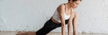 Photo for Young slim brunette fitness woman stretching on a sports mat in the studio side - Royalty Free Image