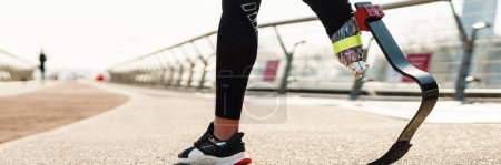 Foto de Joven deportista con prótesis caminando sobre puente de la ciudad - Imagen libre de derechos