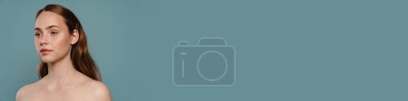 Téléchargez les photos : Femme roux à moitié nue posant et regardant de côté isolé sur fond bleu - en image libre de droit
