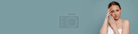 Téléchargez les photos : Femme roux avec boutons couvrant son visage et regardant la caméra isolée sur fond bleu - en image libre de droit