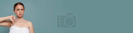 Téléchargez les photos : Femme roux portant une serviette avec des boutons montrant pouce vers le haut isolé sur fond bleu - en image libre de droit