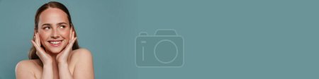 Téléchargez les photos : Femme roux à moitié nue souriant et regardant de côté isolé sur fond bleu - en image libre de droit