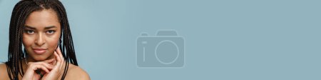 Téléchargez les photos : Jeune femme torse nu noir avec des nattes regardant la caméra isolée sur fond bleu - en image libre de droit