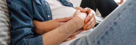Téléchargez les photos : Plan rapproché d'un couple de lesbiennes embrassant le ventre d'une fille enceinte sur le lit dans la chambre - en image libre de droit
