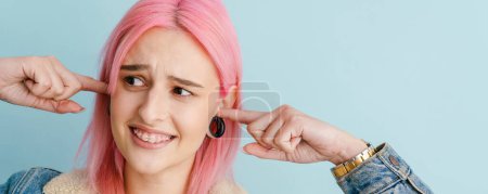 Photo for Young white woman with pink hair smiling and plugging her ears isolated over blue background - Royalty Free Image
