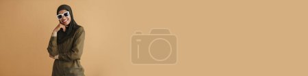 Téléchargez les photos : Femme musulmane noire en hijab souriant et regardant la caméra isolée sur fond beige - en image libre de droit