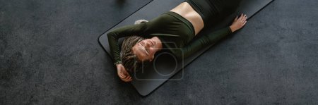 Téléchargez les photos : Jeune sportive avec prothèse couchée sur le tapis tout en travaillant à l'intérieur - en image libre de droit