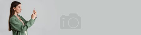 Téléchargez les photos : Heureuse fille caucasienne souriant et prenant des photos sur téléphone mobile isolé sur fond blanc - en image libre de droit