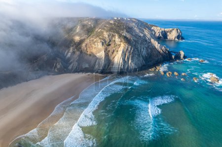 Drohnenaufnahme des Strandes von Cordoama in Portugal mit Sandstrand, Klippen und Meer