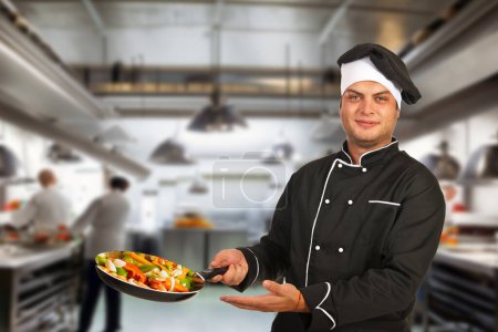 Adult chef in cafe kitchen, dressed in uniform, working on food preparation.