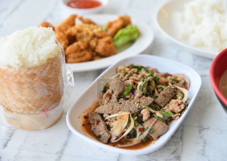 Foto de Ensalada picante de hígado de cerdo asado con arroz pegajoso al lado, cocina tailandesa - Imagen libre de derechos