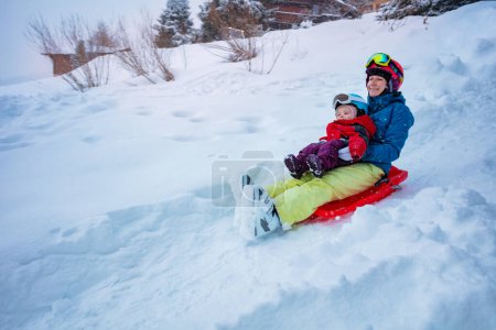 Photo for Mother with little girl sled downhill on the sledge from the hill at winter vacations - Royalty Free Image