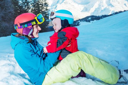 Photo for Young happy mother play with daughter girl both wearing ski outfit helmet and mask - Royalty Free Image
