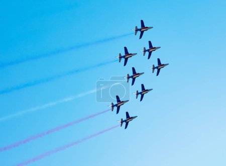 Téléchargez les photos : Squadron of planes fly with color trail in blue red white lines over clear sky in colors of USA Holland or France - en image libre de droit