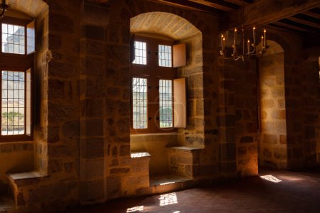 Téléchargez les photos : Dark old castle building interior with stone walls and wooden ceiling, little lights pass through windows - en image libre de droit