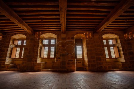 Foto de Antiguo edificio del castillo interior con paredes de piedra y techo de madera, lámparas colgantes - Imagen libre de derechos