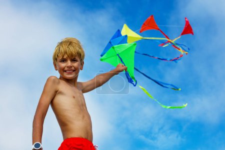 Photo for Young smiling boy close portrait stand holding many colorful kites in hand over blue sky - Royalty Free Image