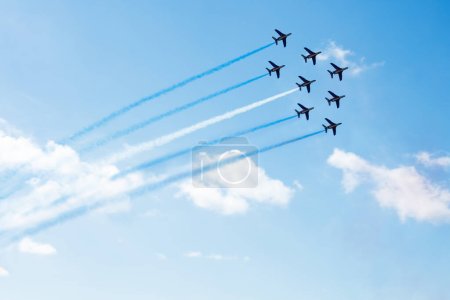 Téléchargez les photos : Squadron of planes fly with color trail lines of Finland Israel Greece Honduras Argentina Micronesia Guatemala or El Salvador over clouds and clear sky - en image libre de droit
