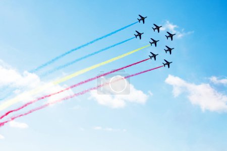 Téléchargez les photos : Escadron d'avions volent avec des lignes de sentiers de couleur de la Moldavie, la Roumanie, la Colombie ou l'Équateur sur les nuages et le ciel clair - en image libre de droit