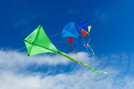 Téléchargez les photos : Groupe de six nombreux beaux cerfs-volants colorés volent sur la corde au-dessus du ciel bleu avec des nuages - en image libre de droit