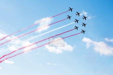 Foto de Escuadrón de aviones vuela con líneas de sendero de color de Polonia Singapur Perú Mónaco Malta Letonia Indonesia Dinamarca Austria sobre nubes y cielo despejado - Imagen libre de derechos