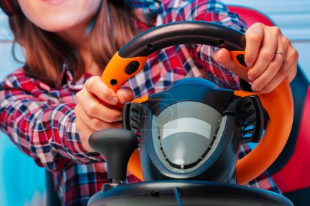 Photo for Close-up of hands on console steering wheel of a gamer woman playing race game - Royalty Free Image