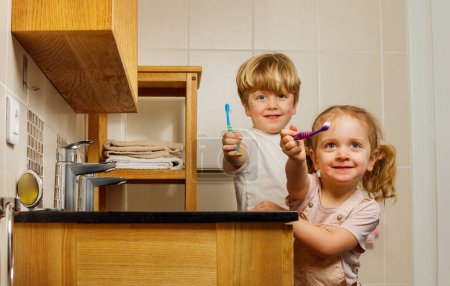 Foto de Dos hermanos felices, una hermana, un hermano, son capturados en cámara mientras se cepillan los dientes y muestran sus sonrisas al espectador - Imagen libre de derechos