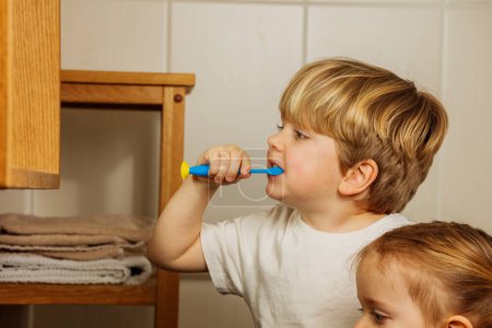 Foto de Perfil retrato de un niño rubio cepillándose los dientes con cepillo de dientes - Imagen libre de derechos
