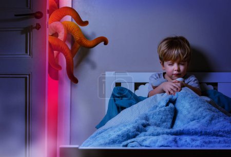 Foto de Niño en el dormitorio cerrar los ojos para no ver monstruo pesadilla con tentáculos entrar en la habitación - Imagen libre de derechos
