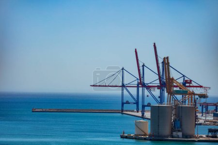 Photo for Cargo terminal and industrial big metal port cranes in the Malaga bay in Mediterranean sea - Royalty Free Image