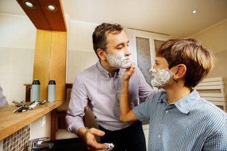 Téléchargez les photos : Adolescent moussant papa visage avec sa main rasage ensemble, père et fils collage - en image libre de droit