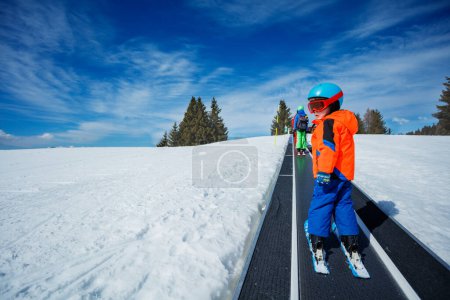 Foto de Dos chicos en la pista de esquí moviéndose cinturón en la escuela de esquí durante las vacaciones de invierno vista desde atrás - Imagen libre de derechos