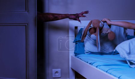 Foto de La mano monstruosa con los gateos tratando de agarrar el juguete de peluche del niño en la cama - el sueño infantil teme el concepto - Imagen libre de derechos