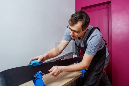 Photo for Man in a workshop prepare skis with care, sharpening edge using sharp tool - Royalty Free Image