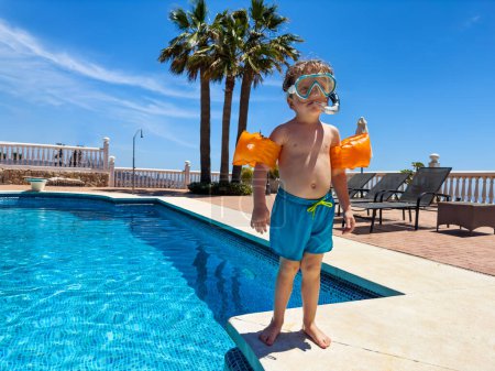 Photo for Little diver boy in swimming mask standing on the edge of resort pool ready to dive and have fun - Royalty Free Image
