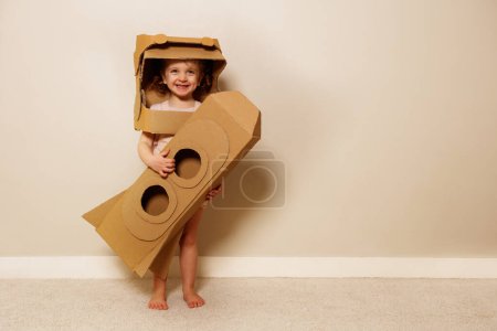 Photo for Beautiful young girl wear a cardboard helmet while holding his homemade rocket as she imagined voyaging through the mysteries of outer space - Royalty Free Image