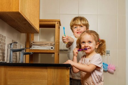 Photo for Portrait of two happy kids brother and sister with toothbrush in hands brushing teeth show them to camera smiling - Royalty Free Image