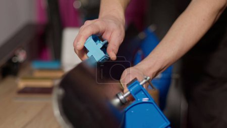 Photo for Close-up image of a man sharping ski edges with sharpening tool at the workshop holding skies in vice - Royalty Free Image