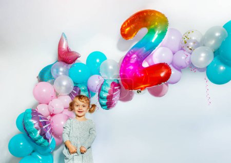 Foto de Niña de pie sobre las decoraciones y el número dos 2 en la fiesta de cumpleaños del niño en casa - Imagen libre de derechos