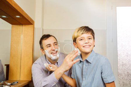 Téléchargez les photos : Papa toucher face à mousse riant adolescent avant sa première expérience de rasage - en image libre de droit