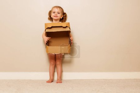Photo for Happy smiling little girl holds cardboard astronaut helmet dreaming to explore space - Royalty Free Image