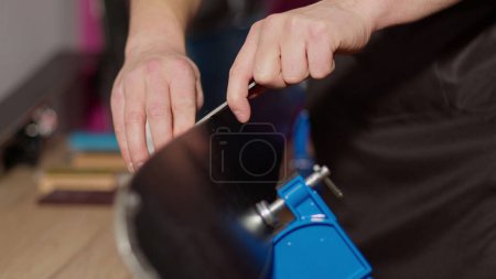 Photo for Close-up image of a man sharping ski edges with file tool at the workshop holding skies in vice - Royalty Free Image
