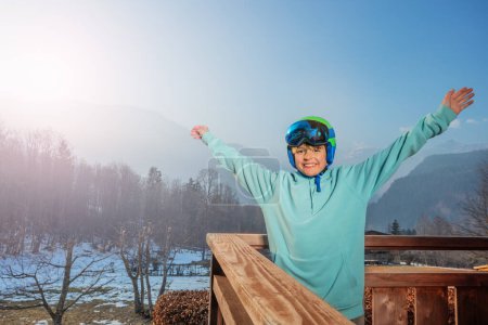 Foto de Feliz esquiador de pie en el balcón sobre el bosque nebuloso y las montañas, levantando las manos - Imagen libre de derechos